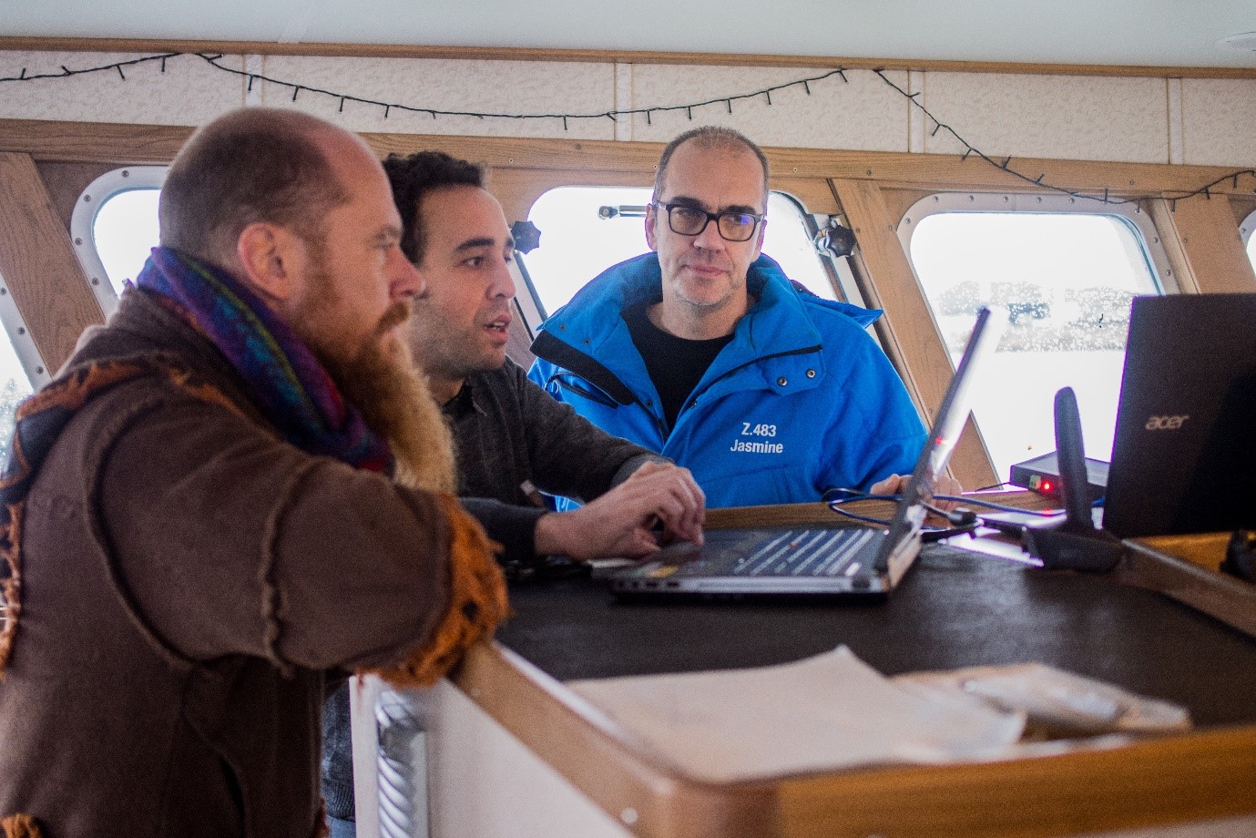 3 mannen op een vissersboot bij een laptop