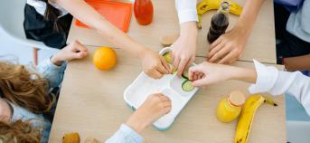 5 handen eten fruit aan schooltafel